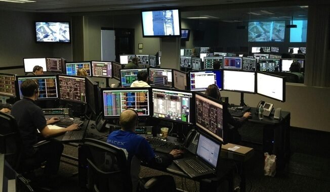 Team members focused on cyber security, analyzing data across several computer screens in a collaborative workspace.