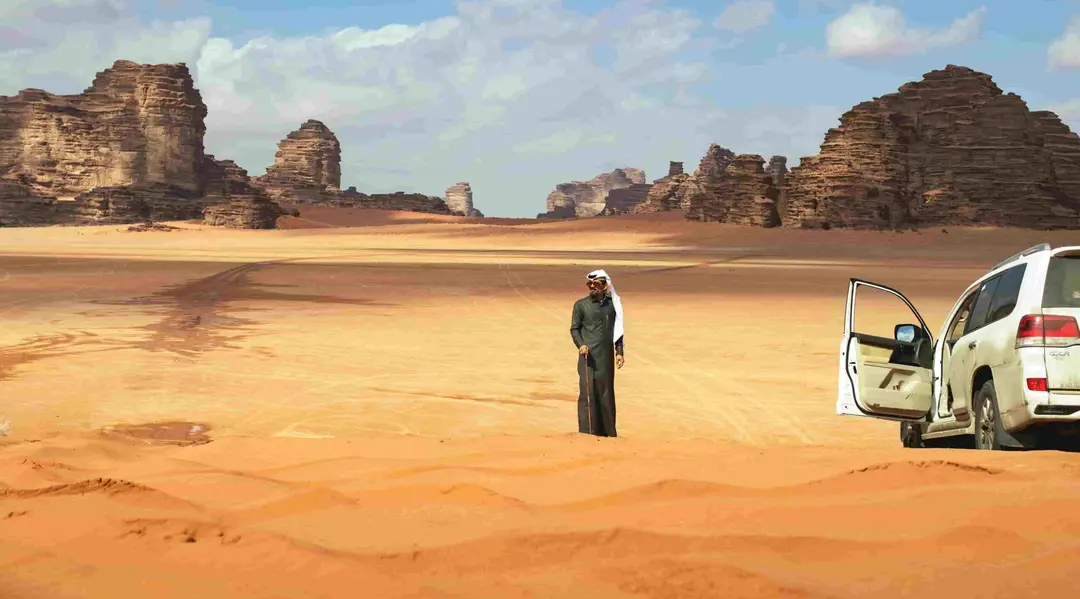 Expansive view of Wadi Rum's red desert landscape, featuring towering sandstone cliffs and a clear blue sky.